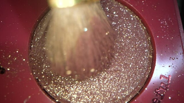 This macro video shows a close u view of a makeup brush using pink metallic eye glitter shadow.