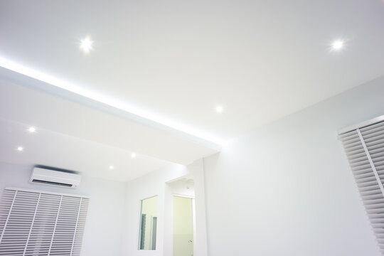 LED strip light and illumination. Also called ribbon light or LED tape to suspended on ceiling in plasterboard in empty living room include down light, white wall. Interior home design and technology.