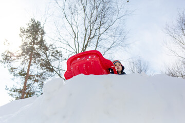 Low angle view of a boy sledding on a snow hill in winter