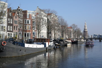 cityscape of traditional brick houses and boat houses floating in canal of winter amsterdam