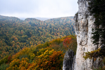 The Röthelfels with trees in bright autumn colors and further rocks at Gößweinstein, Franconian Switzerland, Germany