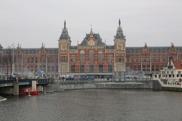 historical architecture of amsterdam station in front of the canal in winter netherlands - obrazy, fototapety, plakaty