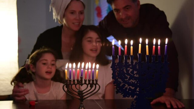 Jewish family pray, sing and look at candelabrum (hanukkiah) on the eight day of Hanukkah Jewish holiday festival commemorate the rededication of Jerusalem Second Temple in the 2nd century BCE.