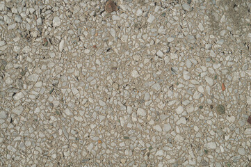 The texture of the old concrete pavement. Inclusions of small stones in the concrete floor.