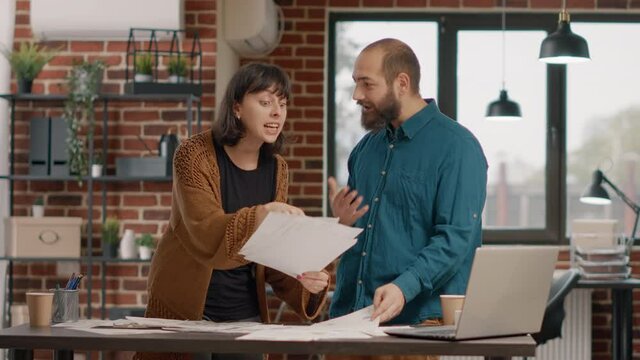 Angry woman throwing papers in air after conflict with man, working on business project design and charts. Workmates having argument and dispute at work, fighting over strategy ideas.