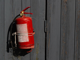 red fire extinguisher on a wooden wall