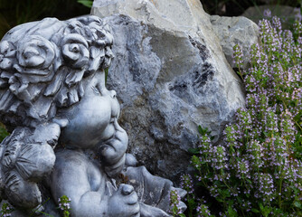 cupid on a background of stone and thyme bushes, looks to the right