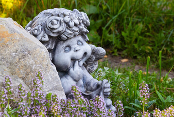 the figure of an angel behind a stone on a background of greenery