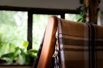 a fragment of a chair and a plaid in a cage on the background of a window
