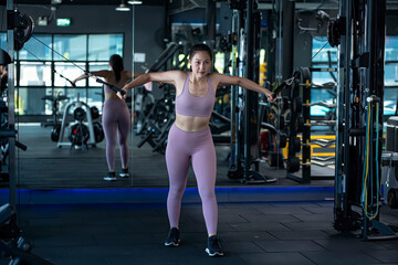 Beautiful young caucasian female athlete exercising with cable crossover machine in fitness Gym