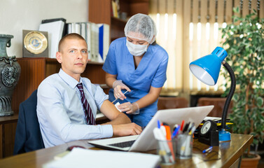 Doctor in a protective mask injects a vaccine to a man with a syringe