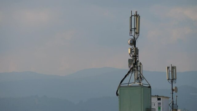 Mobile phone communication tower on building roof on mountain and sky background. Technology of telecommunication GSM tower. 5G or 4G concept
