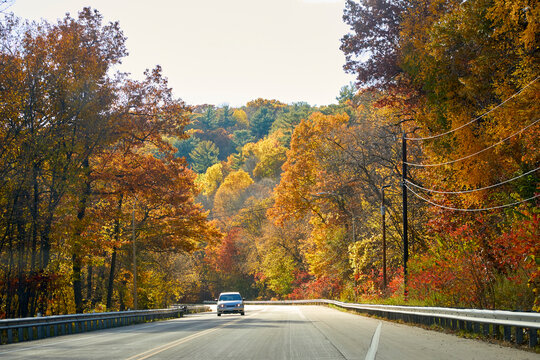 Car traveling down the road with beautiful leaves turning vivid colors on a country highway