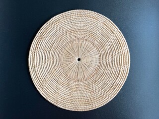 Round shape woven rattan placemat on black background, handmade kitchenware, weave craft product 