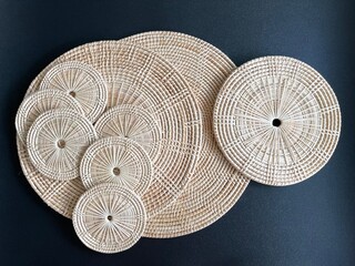 Round shape woven rattan placemat on black background, handmade kitchenware, weave craft product 