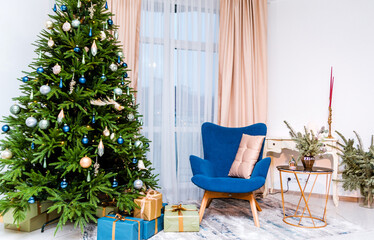 Stylish and modern New Year's interior of the room. In the kmnat there is a Christmas tree with gifts, a blue armchair, a table with New Year decor