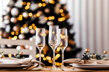 Beautiful set up indoor. Served table with three empty champagne glasses, warm colors, blurred background.