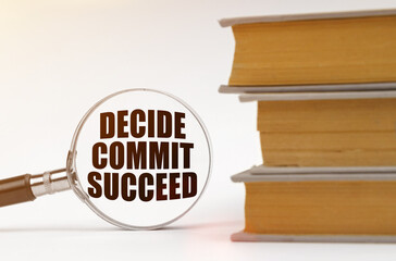 On a white background, books and a magnifying glass, inside which it is written - Decide Commit Succeed