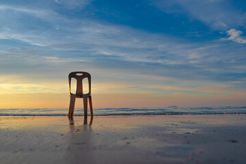 Old white chair on the beach in Thailand a beautiful morning sky
