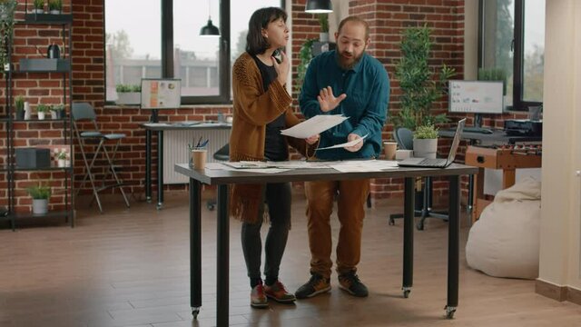 Workmates arguing and fighting about business project, trying to work on papers with rate charts. Aggressive woman throwing files in air while having argument and quarrel with man.