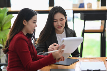 Two successful businesswoman discussing and checking reports together.