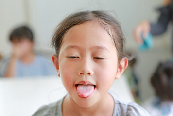 Funny face Asian little girl child showing stick tongue out