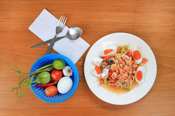 Papaya Salad (Som Tam) with salt egg and shrimp the traditional Thai foods on wood table background. Most wanted popular food in Thailand. Top view.