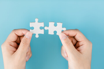 Close up of hand women connecting pieces of a jigsaw puzzle on a blue background, business connection, success, solution, and strategy concept.