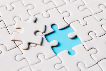 Top view of white jigsaw puzzle connecting pieces of a jigsaw puzzle on a blue background, business connection, partnership or teamwork success, solution, and strategy concept.