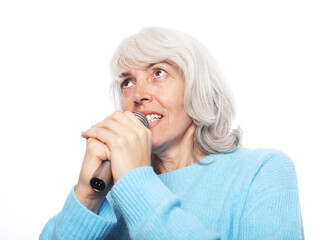 Happy old woman holding a microphone and singing