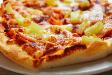 Close up of Pizza with pineapple,  mozzarella cheese, ham, bacon, pizza sauce. Sliced Hawaiian...