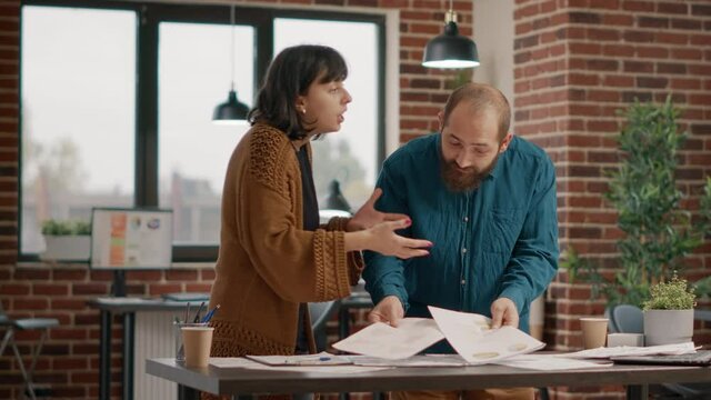 Workmates having argument about project planning, trying to work on business strategy. Aggressive man throwing papers in air and fighting with woman. Colleagues in conflict having dispute