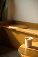 Cup of coffee with milk put on a chair in sunlight shade cafe with cozy room