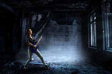 Young and beautiful rock girl playing the electric guitar