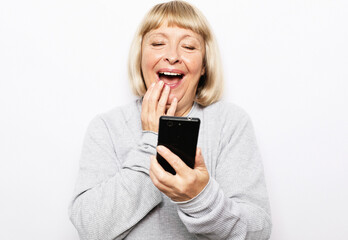 Fototapeta premium Image of a happy surprised shocked old woman using mobile phone.