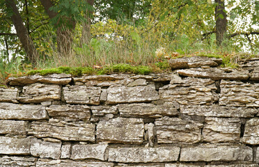 old stone wall of blocks of bricks and stones with grass