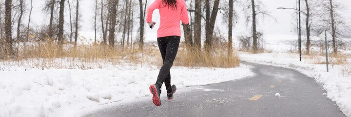 Winter running shoes on ice and snow. Banner crop of slippery road. Athlete runner training outside...