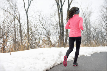 Winter fitness running woman jogging in park. Athlete runner from behind training cardio wearing...