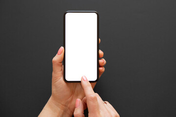 Woman using mobile phone with empty white screen on dark background