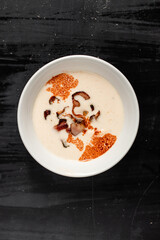 mexican cream soup, food with meat, bacon parsley in a white plate on a black background