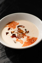 mexican cream soup, food with meat, bacon parsley in a white plate on a black background