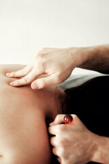A male masseur conducts spa treatments with a special massage roller. for a young woman who is lying face down on the couch.