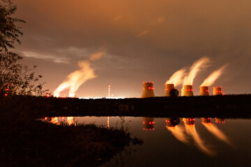 The lights of a nuclear power plant are reflected in a pond. Nuclear power plant cooling towers