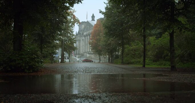4k video of the Berlin Reichstag in autumn during a rain. A puddle in the foreground