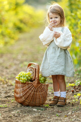 Beautiful little girl with grapes. Child with fruit. High quality photo