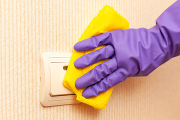 female hand in a rubber glove disinfects the room switch
