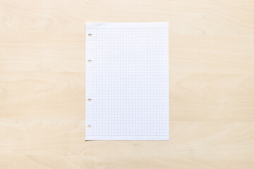 top view of blank sheet of squared paper on light brown wooden board