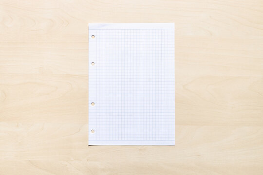 top view of blank sheet of squared paper on light brown wooden board
