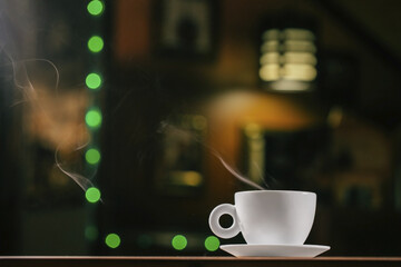 Coffee in white cup surrounded by coffee beans on dark background with copyspace
