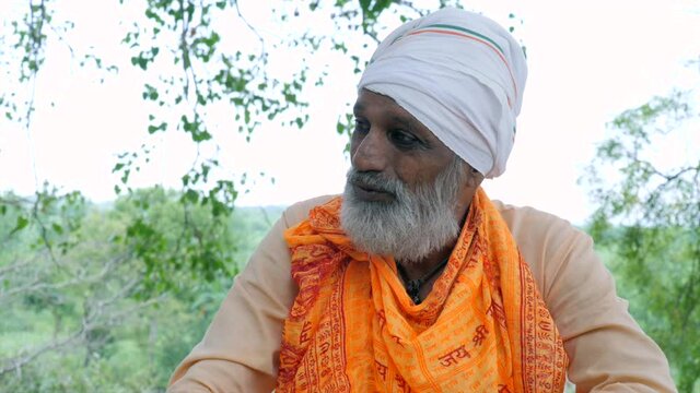 Hindu Pandit wearing a stole with Indian God's name. A bearded saint (Sadhu) covering his head with a white cloth (Safa) smiling 